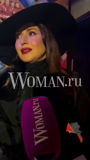 Жасмин в чёрной шляпе и выразительным макияжем; боковой портрет с логотипом Woman.ru и фиолетовым микрофоном в кадре, интервью на мероприятии.
