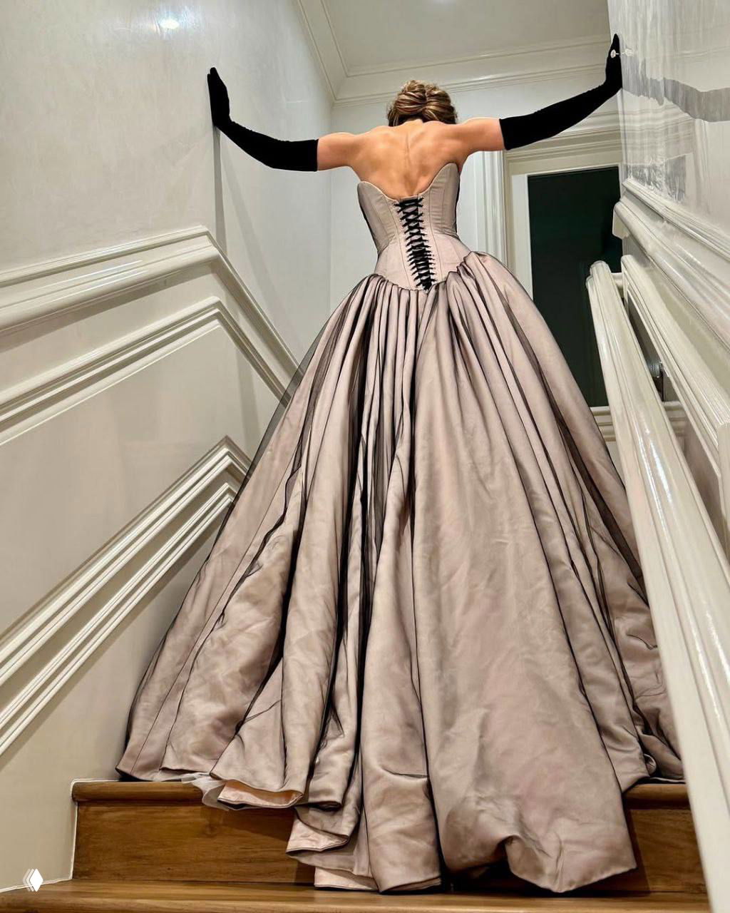 Задний план наряда: корсет со шнуровкой и объёмная юбка в бежево‑серых тонах, вид со спины по лестнице.