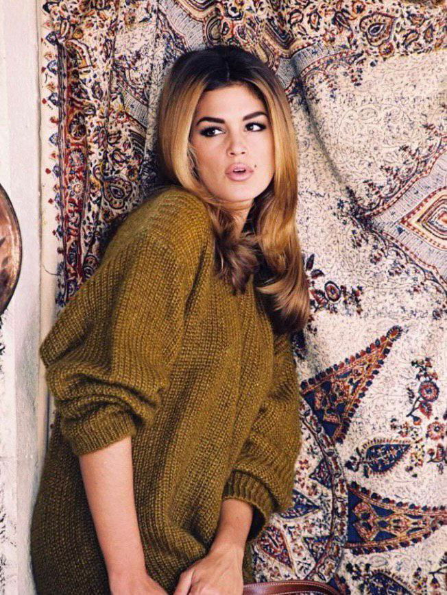 Портретная архивная фотография модели в тёплом вязаном свитере на фоне декоративного ковра, естественный макияж, атмосфера 1990‑х.