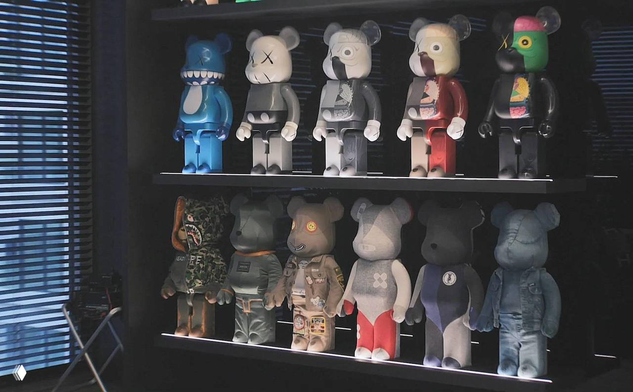 Стеллаж с коллекцией дизайнерских фигурок в стиле Bearbrick разных цветов и дизайнов на подсвеченной полке в кабинете