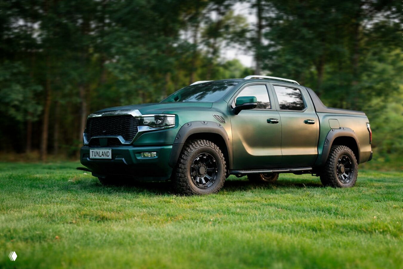 Зелёный пикап Tunland на травяной поляне у леса, акцент на колёса, решётку радиатора и прочный кузов.