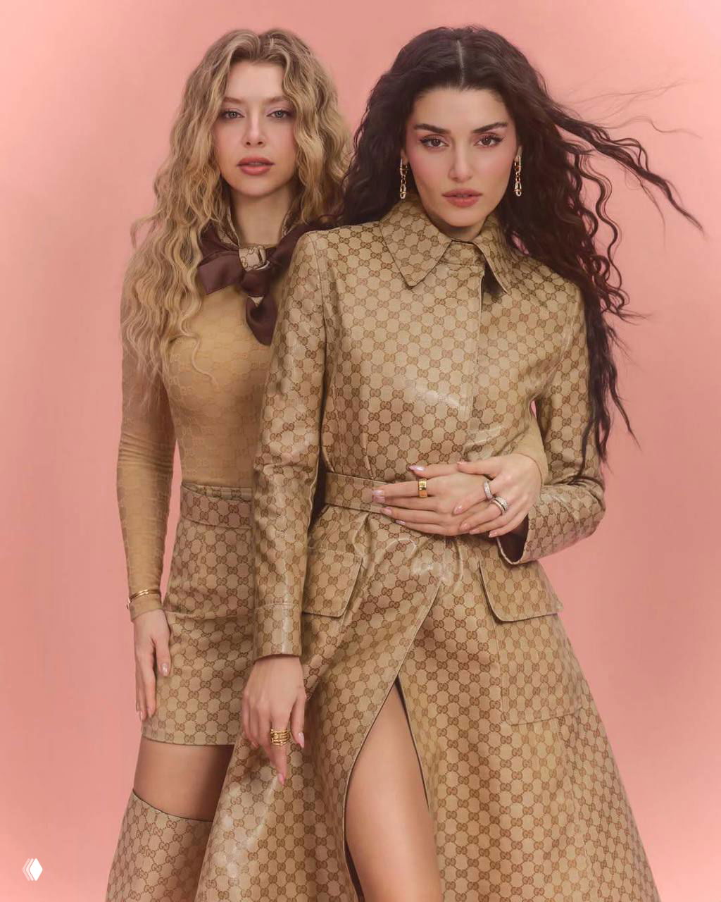 Две женщины в стильных пальто и платьях позируют на розовом фоне в элегантной студийной съёмке модного журнала.