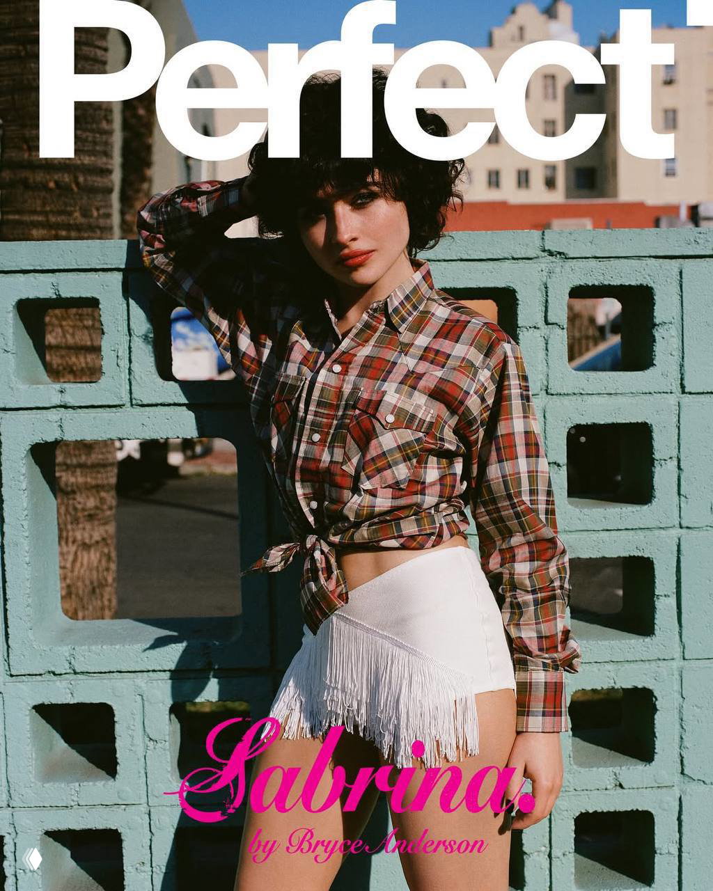 Сабрина Карпентер на уличной фотосессии для обложки Perfect: клетчатая рубашка, белые шорты с бахромой и городской фон.