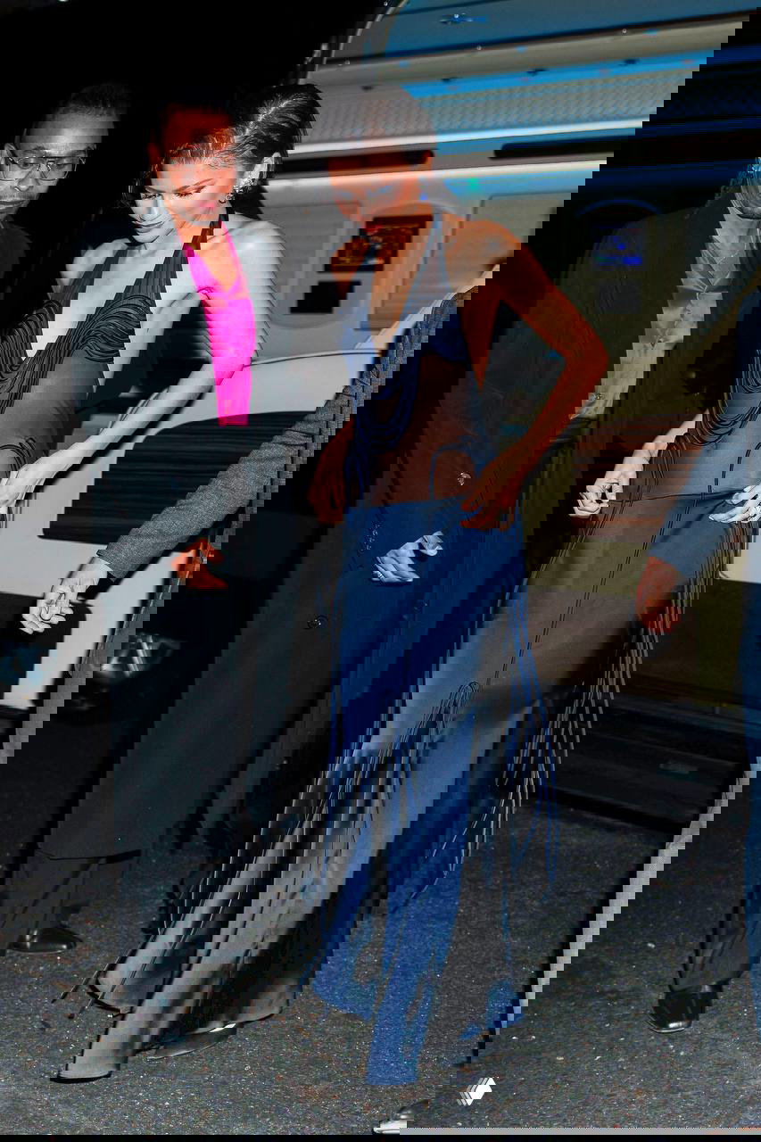 Зендея в темно‑синем сатиновом платье с полупрозрачным корсетом выходит из автомобиля ночью на мероприятии промо-тура; акцент на аксессуарах и силуэте.