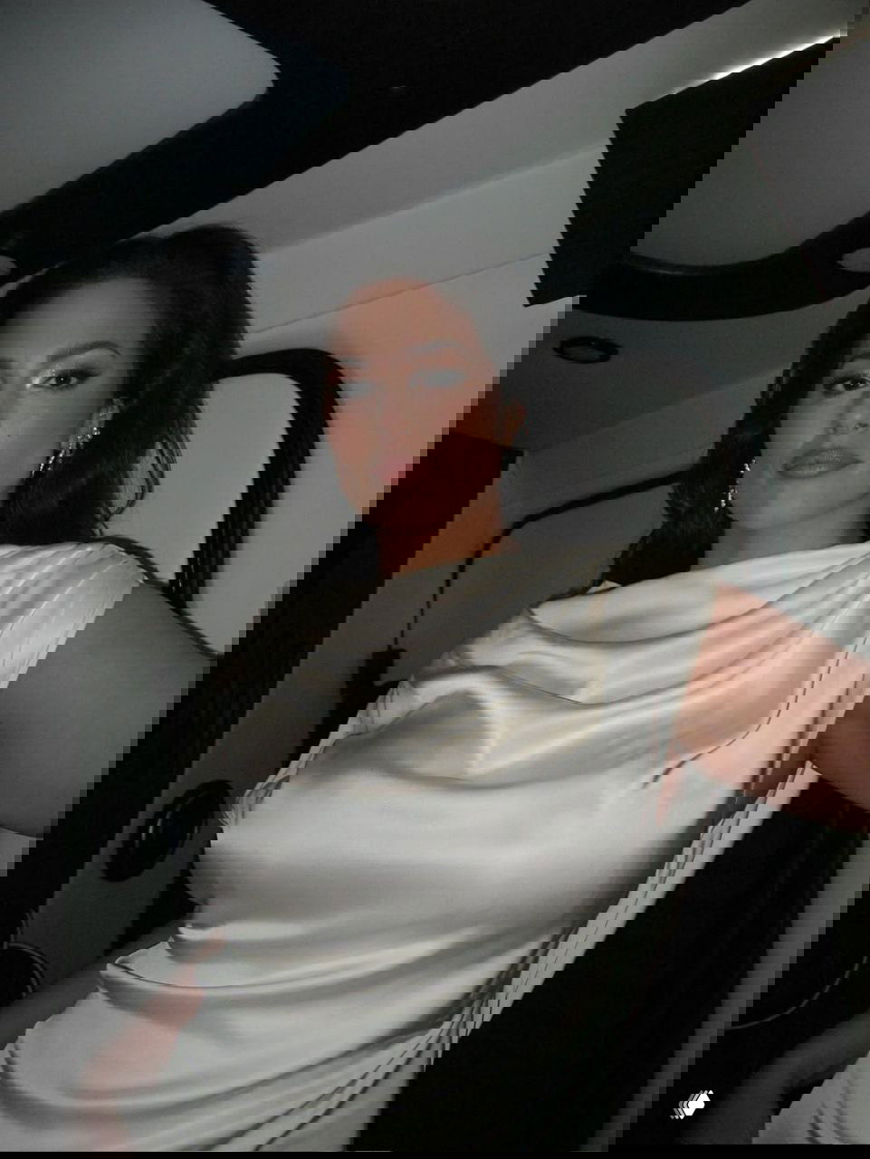 Крупный план портрета женщины в атласном платье с драпировкой, макияж и украшения в вечернем образе; студийное освещение.