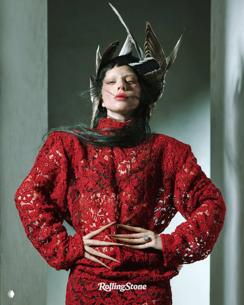 Леди Гага в красном кружевном платье и перьях на голове: статная поза и художественный свет, запечатлённые для кавер-стори Rolling Stone, высокомодный образ студийной съёмки.