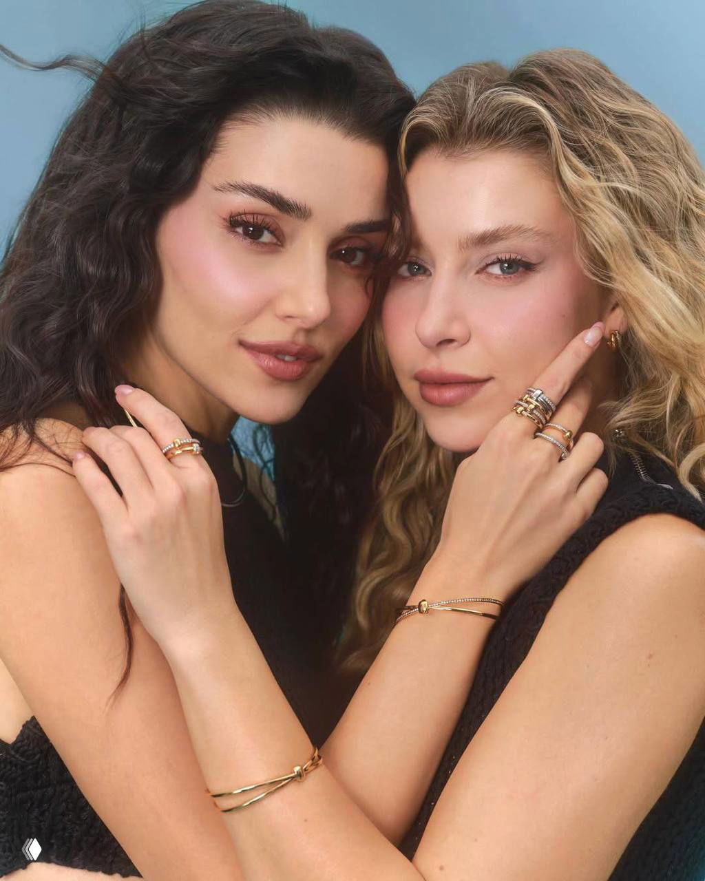 Крупный кадр двух женщин в объятиях: студийная портретная фотография с акцентом на макияж и украшения.