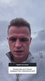 Крупный план мужчины на открытом воздухе при пасмурной погоде, видны гирлянды и серое небо, вертикальная телефонная съёмка