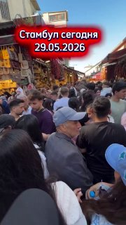 Толпа людей в узком базарном переулке Стамбула 29 мая 2026 года; плотное движение пешеходов, теснота между стойками и витринами.