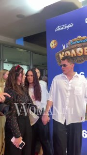 Максим Зайц и спутницы у баннера фильма на премьере: кадр с улыбками, гости в светлой и тёмной одежде на фоне рекламного стенда.