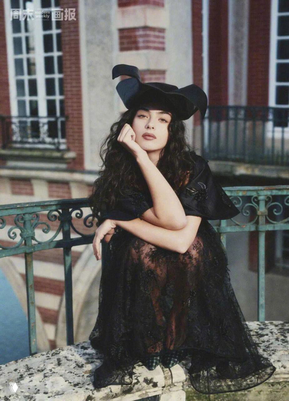 Модель в чёрном платье и кружевном низе присела у балюстрады замка: сочетание готики и романтики в кадре.