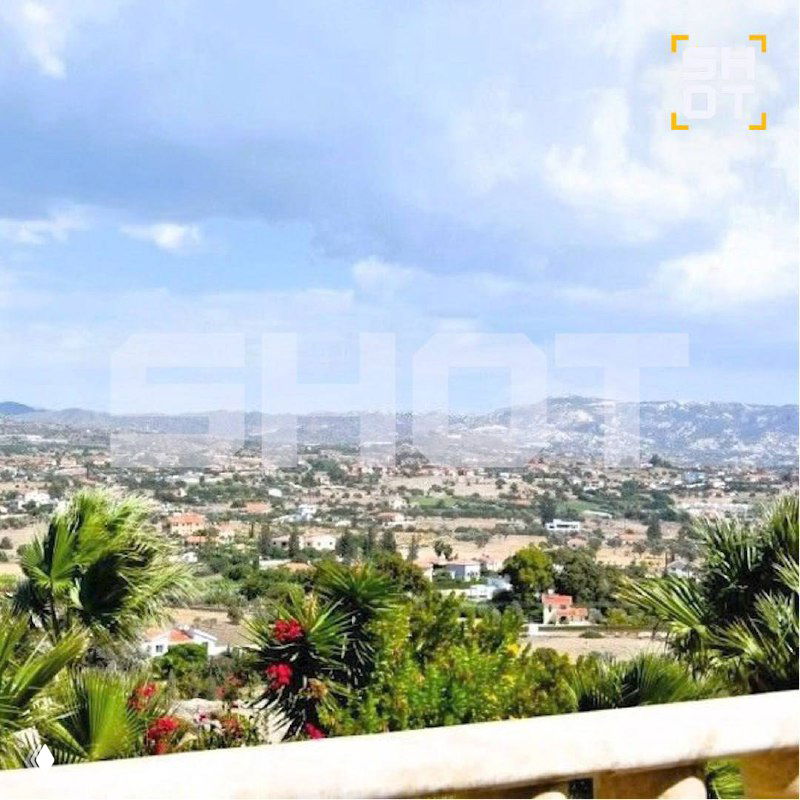 Панорамный вид с террасы на окружающий ландшафт и холмы около Лимассола, видны кустарники и дальние постройки на фоне неба