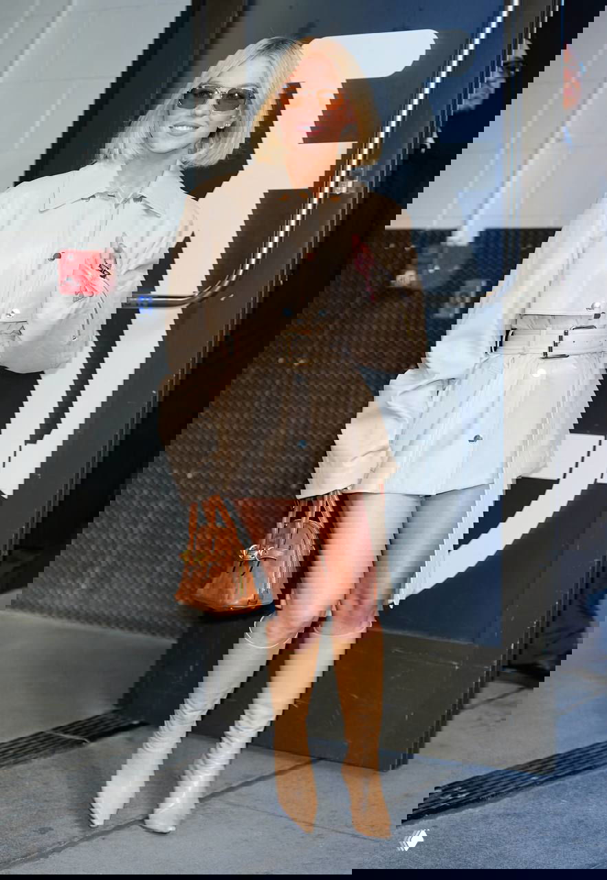 Актриса в кремовом кожаном плаще с поясом и бежевых сапогах, короткая стрижка и сумка — городской выход в свет с улыбкой