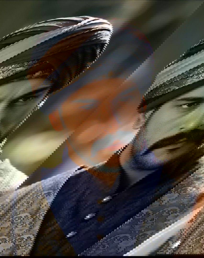 Мужчина в тёмном пальто идёт по городской улице в деловом стиле, уверенная походка, архитектурный фон и прохладная неброская палитра.