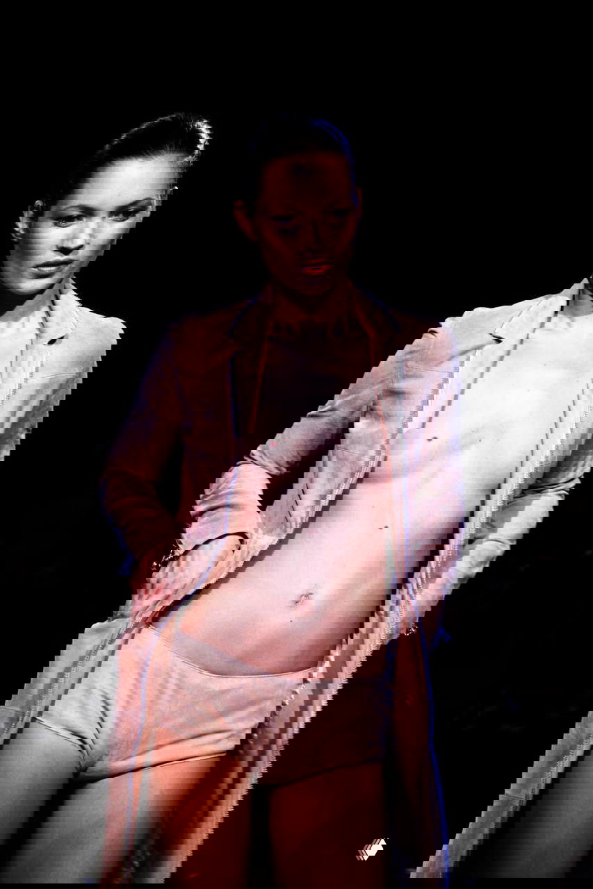 Кейт Мосс в обнажённом или полуартистическом сценическом образе на подиуме, кожаная куртка и короткие шорты — провокационный показ мод с минимализмом.