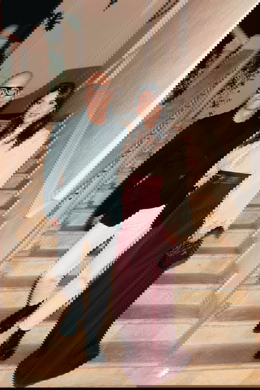 Гости за столом: мужчина сидит, к нему прислонена женщина, рука на плечe — кадр с ужина благотворительного вечера, дружеская обстановка.