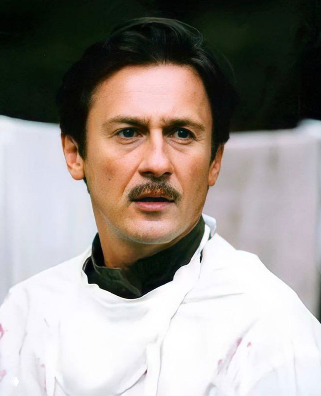 Кадр из фильма: портрет в фас, мужчина в форме с усами, лицо в спокойном выразительном образе, театральный грим и свет постановки.