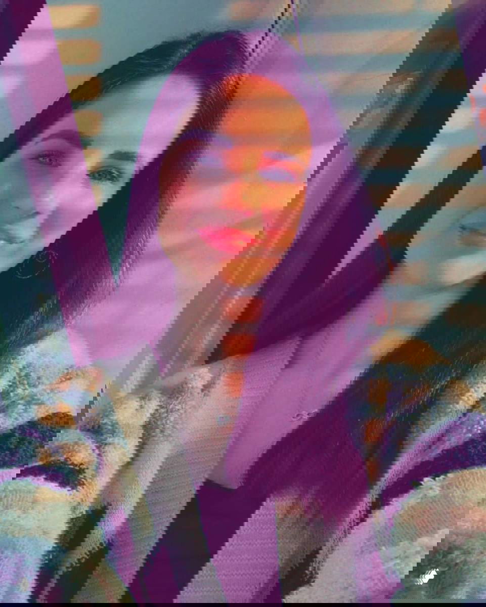 Портрет молодой девушки в помещении при мягком дневном свете; улыбка и естественный образ, крупный план лица и аксессуары.