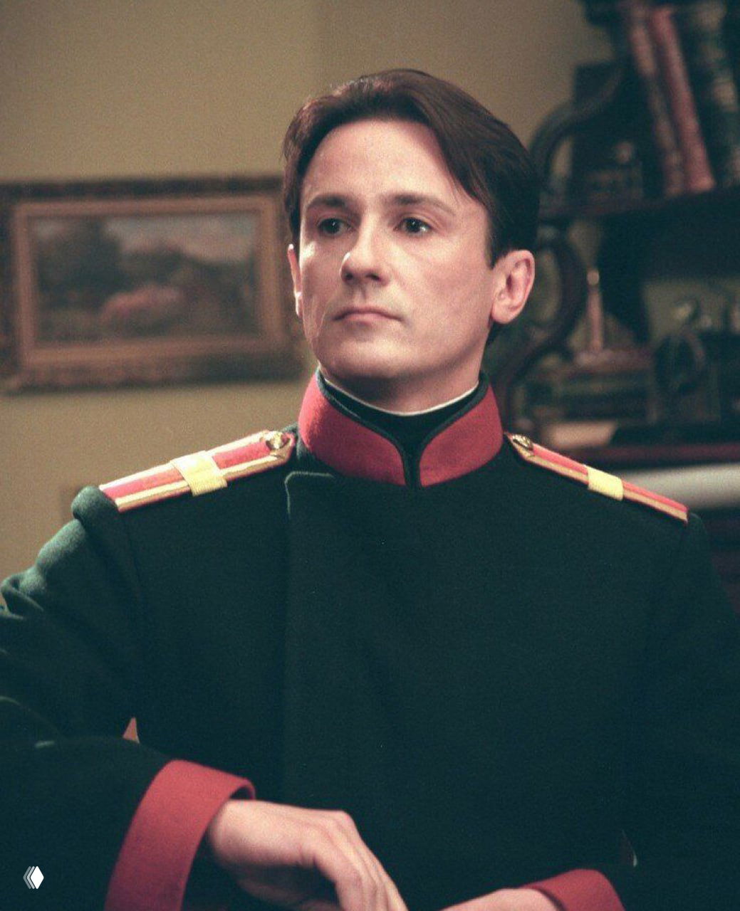 Полуфигура в мундире офицера на светлом фоне, композиция подчёркивает профиль и контрольованный взгляд, атмосферный интерьер за спиной.