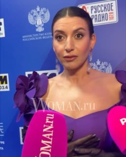 Певица Жасмин в фиолетовом платье на пресс‑мероприятии у микрофонов с логотипами Woman.ru и радиостанций; портретный кадр