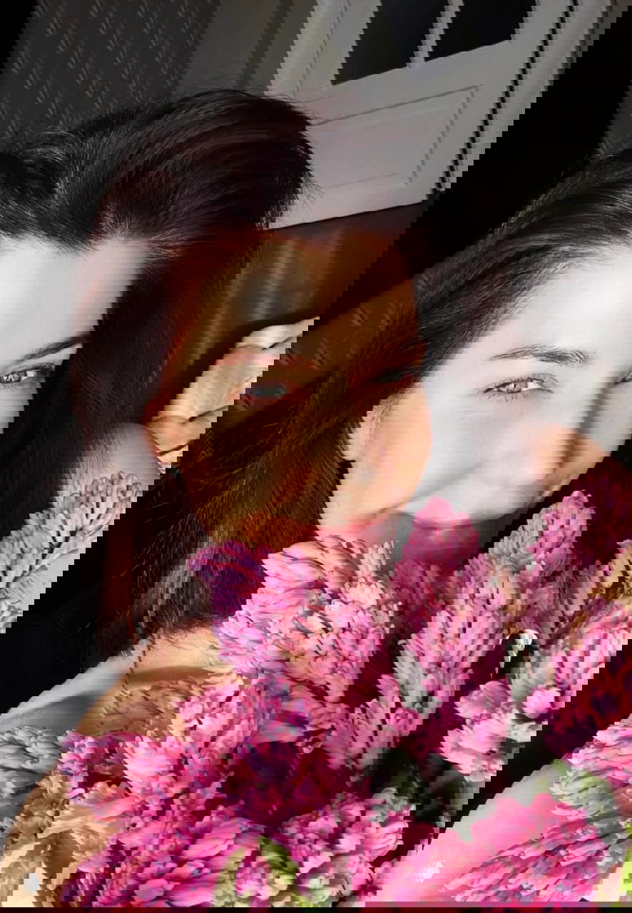 Крупный план селфи женщины с букетом розово‑лиловых гиацинтов, мягкое естественное освещение и улыбка на лице в домашней обстановке