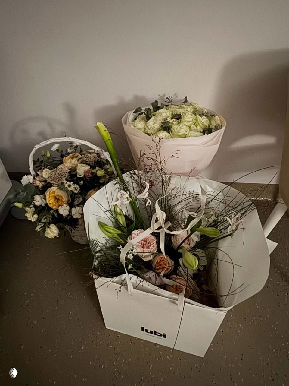 Несколько букетов в коробках и обёртках, подаренные Агате после рождения ребёнка, крупный план цветов и упаковки.