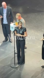 Маш Милаш на сцене во время церемонии у микрофона, держит приз; рядом организаторы и участники события, видно сценическое окружение.