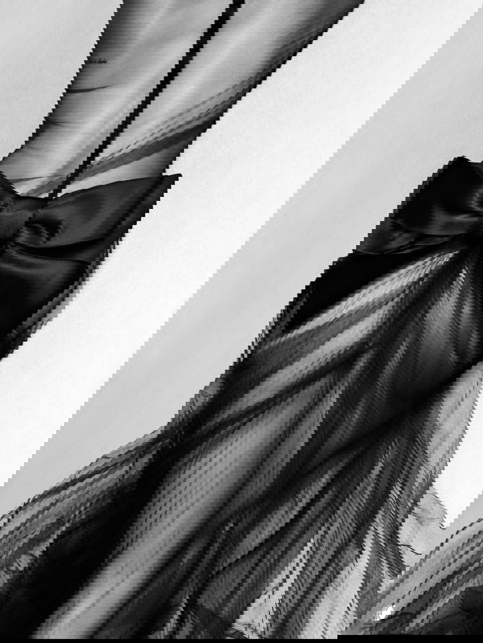 Деталь образа: чёрная прозрачная юбка с большим бантом на талии, крупный план со светотенью и фактурой ткани в художественной съёмке.