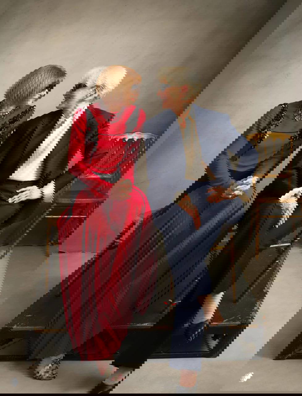 Фото: Мэрил Стрип в строгом костюме и Анна Винтур в красном платье сидят вместе на студийной сцене, обмениваются взглядами.