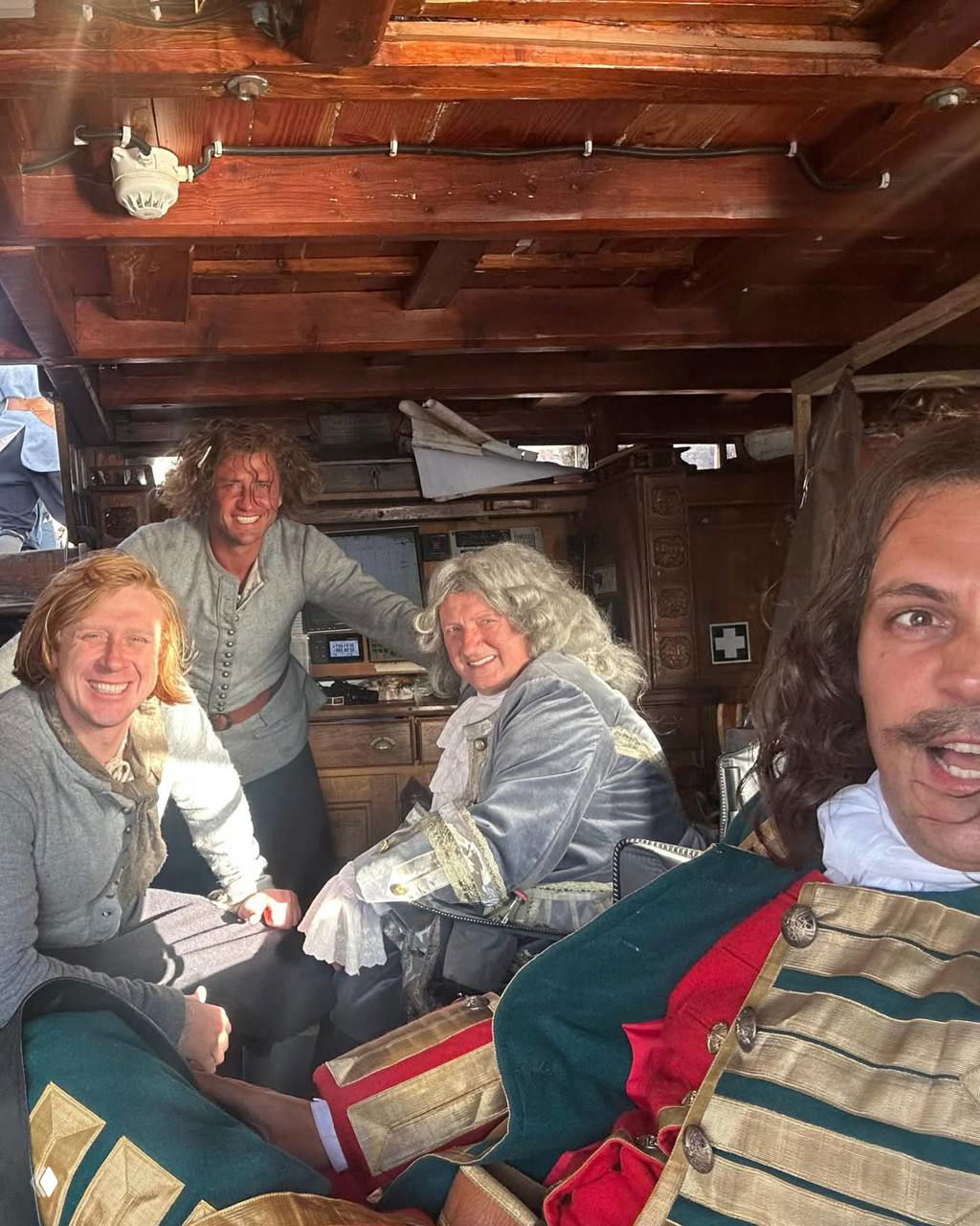 Закадровый снимок в каюте корабля: Милош Бикович и члены съемочной группы улыбаются и отдыхают между дублями.