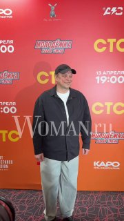 Гость в кепке на красной дорожке перед баннером «Молодёжка. Новая смена», кадр с премьерного показа; водяной знак Woman.ru присутствует.