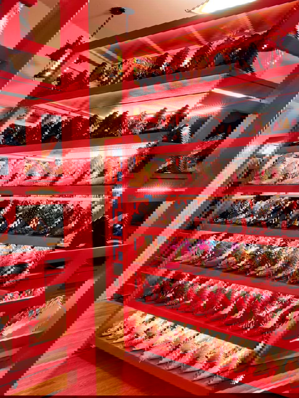 Красные стеллажи с огромной коллекцией туфель на обувной витрине — организованный гардеробный уголок с театральной эстетикой