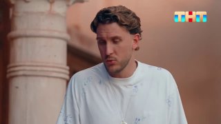 Курбан Омаров в белой футболке на кадре телевизионного шоу с логотипом ТНТ в правом верхнем углу; кадр передаёт эмоцию задумчивости и одиночества.