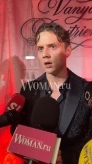 Ваня Дмитриенко в момент интервью на pre-party, лицо с удивлённым выражением, рядом микрофоны и логотип Woman.ru