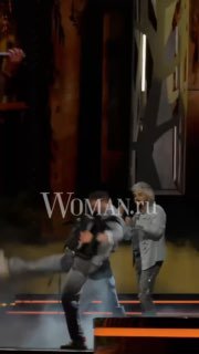 Сцена с двумя музыкантами в яркой подсветке во время концертного номера; артисты в движении, заметны декорации и сцена.