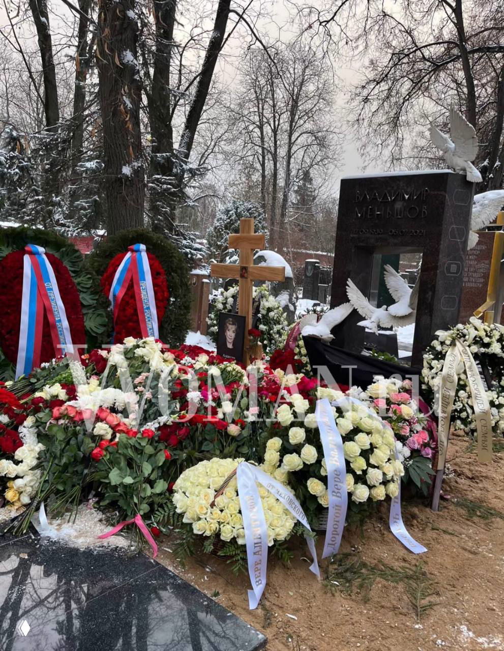 Могила с надгробием, крест и множество венков и цветов на снегу; детали церемонии прощания на Новодевичьем кладбище.