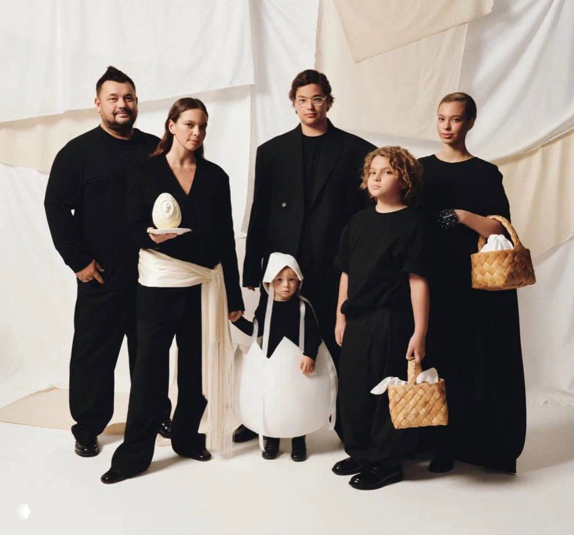 Студийная семейная фотография группы людей в тёмной одежде, держат пасхальные корзины и декор — арт-фото с концептуальной постановкой.