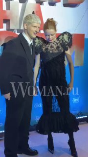 Мила Ершова в смелом чёрном платье и Святослав Рогожан на красной дорожке премьеры сериала «Встать на ноги» в «Синема Парк Мосфильм», водяной знак Woman.ru на переднем плане