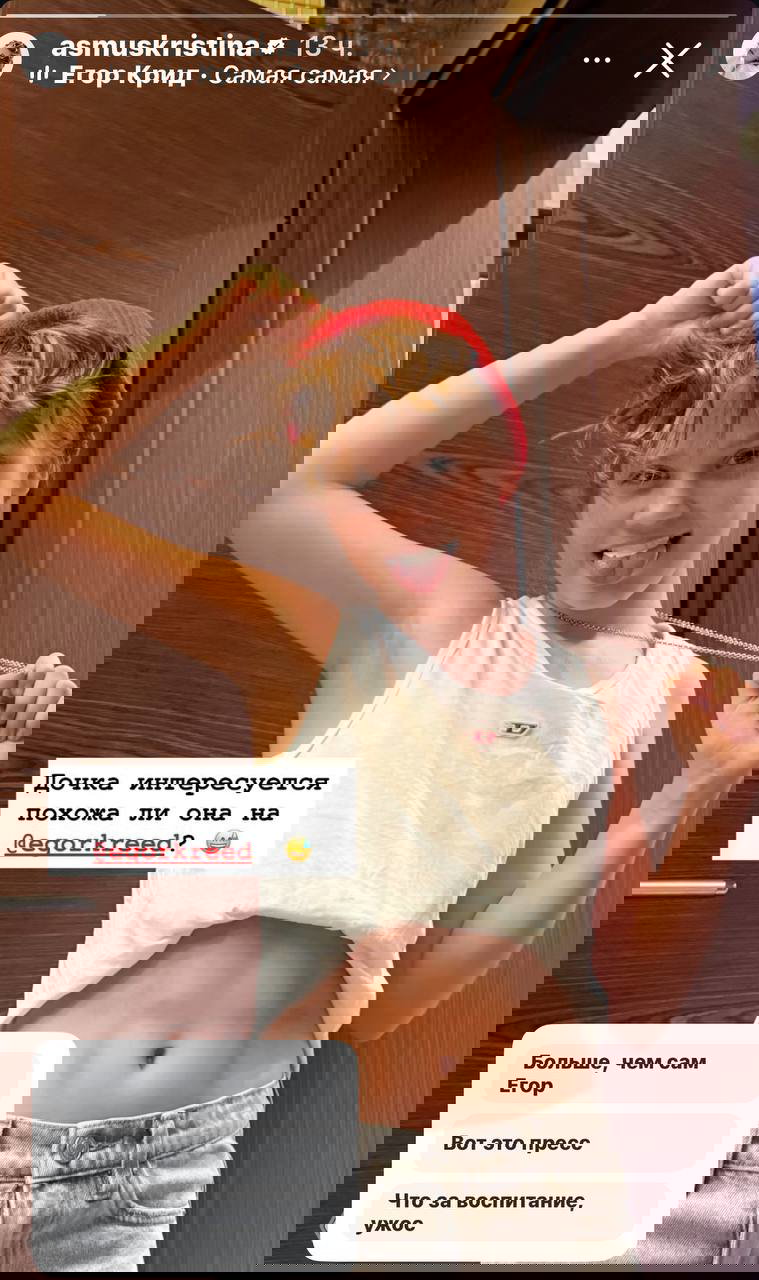 Подросток в шапке и поднятой майке демонстрирует пресс в дверном проёме: игривая поза, снимок в сторис, неэротический контент.