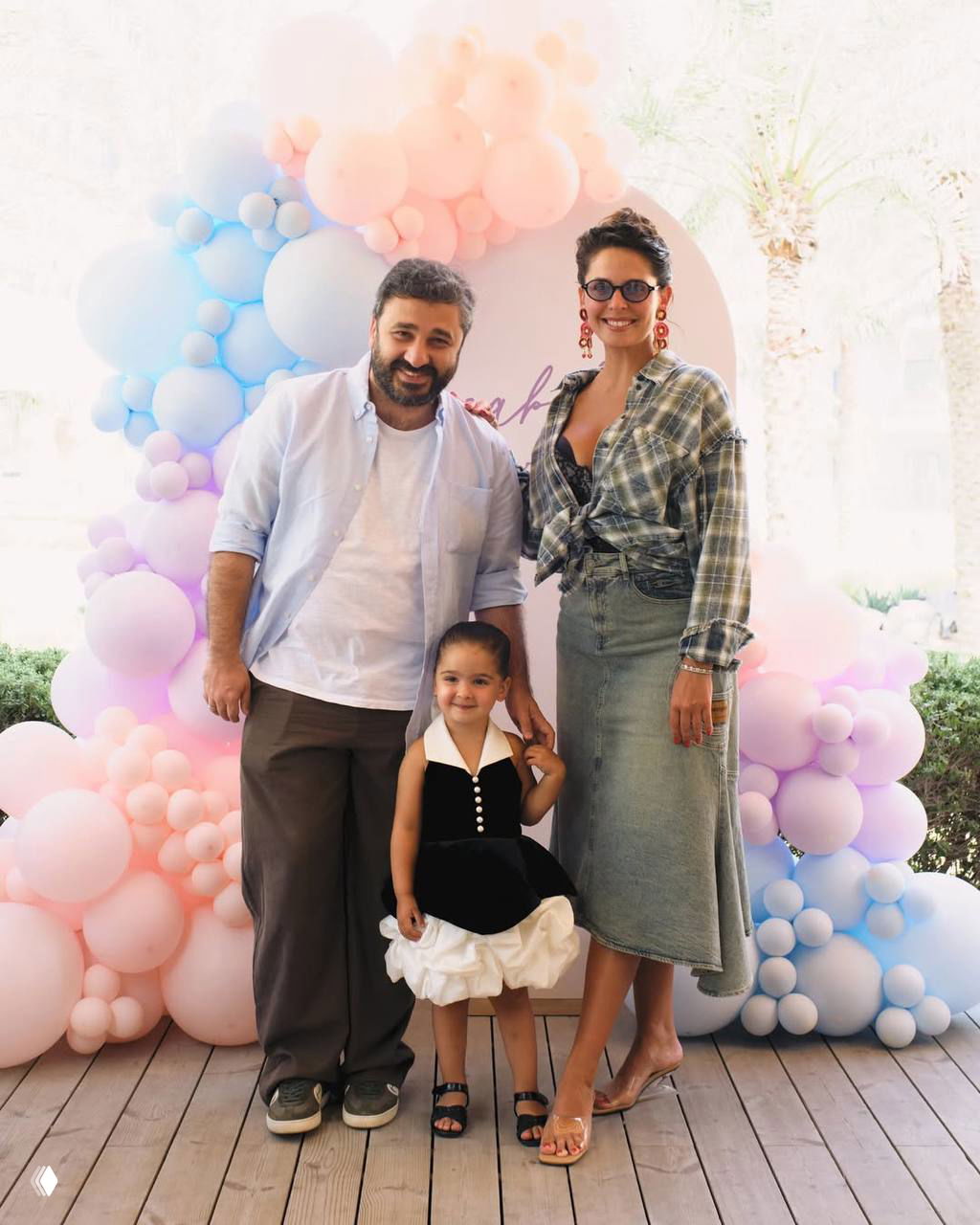 Семейный портрет: Лиза Моряк, Сарик Андреасян и их дочь Элизабет на фоне пастельной арки из шаров — общий кадр с нарядной атмосферой праздника.