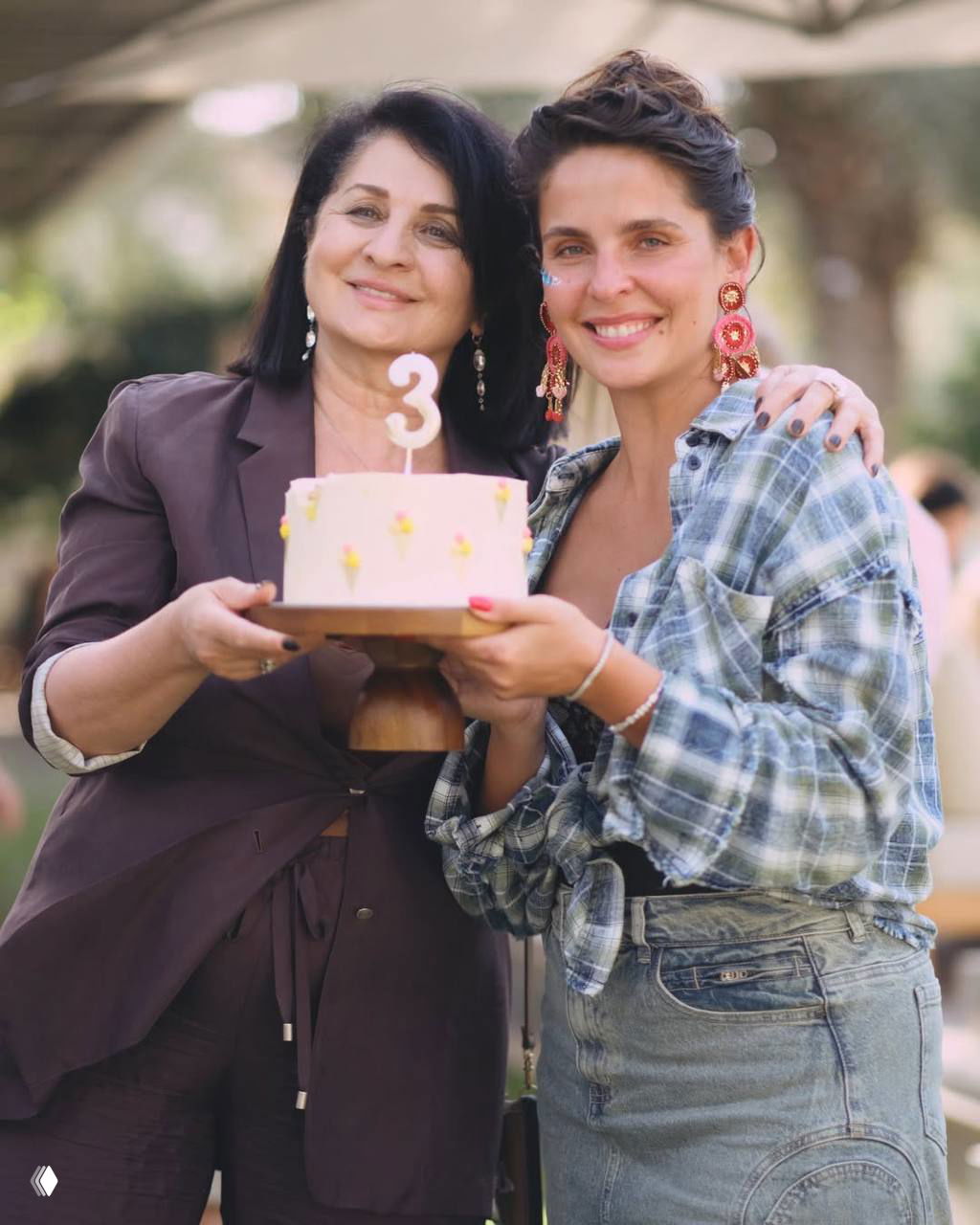 Две женщины держат праздничный торт с цифрой «3»: крупный тёплый кадр с улыбками, вероятно мама и родственница на дне рождения Элизабет.