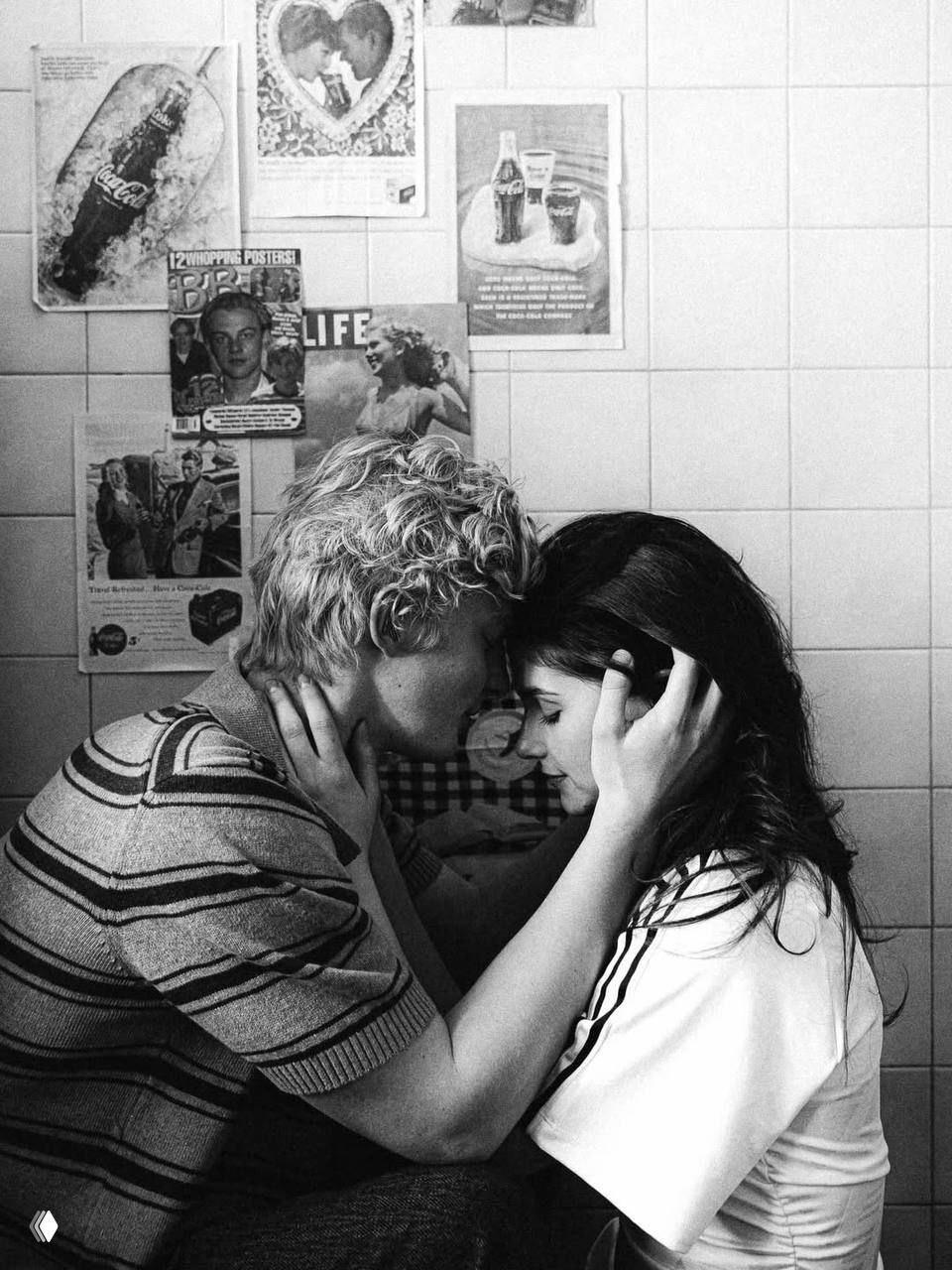 Чёрно‑белый снимок: поцелуй и объятия Полины и Антона на фоне стены с винтажными постерами и рекламой, камерная и ностальгическая сцена.