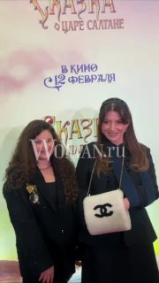 Жасмин на премьере фильма «Сказка о царе Салтане», стоит у баннера, в тёмном пальто с сумкой Chanel; заметен водяной знак WOMAN.ru.