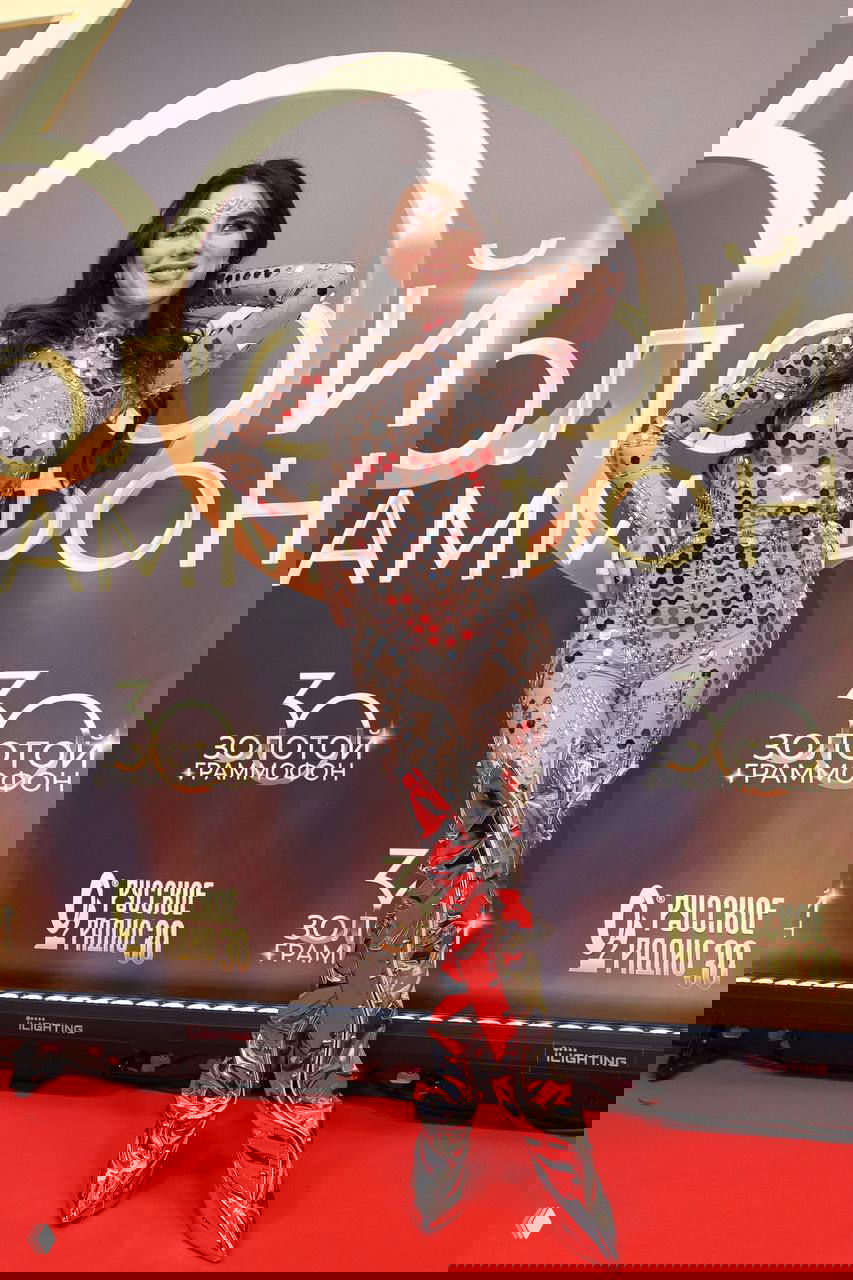 Анна Плетнева в эффектном прозрачном костюме с зеркальными элементами и высокими серебристыми сапогами позирует на красной дорожке — фото с премии 30 лет Русского Радио.