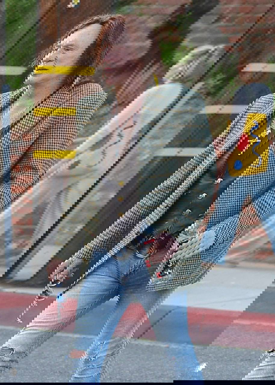 Микки Рурк идёт по тротуару Нью‑Йорка в модных скинни и пиджаке, держит бутылку воды и солнцезащитные очки в руке.