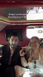Тимур Родригез и Катя Кабак в салоне автомобиля, улыбаются и поднимают бокалы шампанского во время прощальной вечеринки.