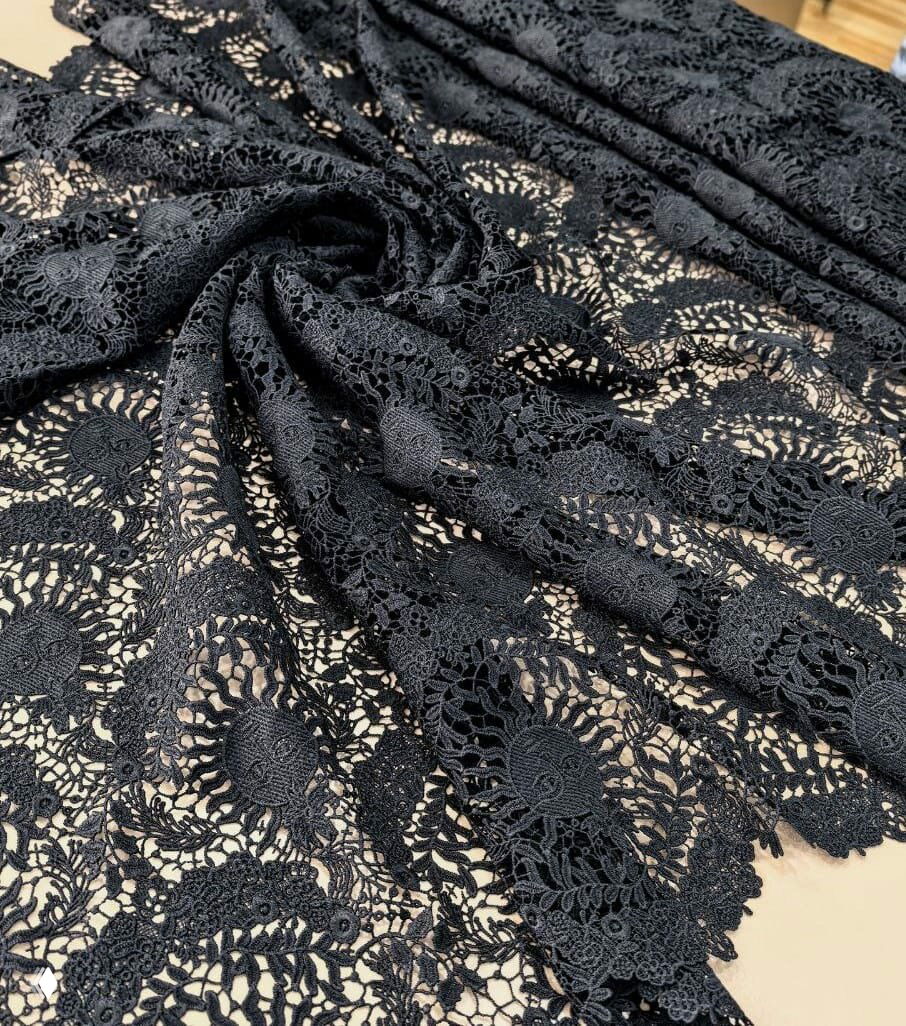 Чёрное кружево крупным планом с плотными и ажурными мотивами, показана фактура, драпировка и сложный узор ткани.
