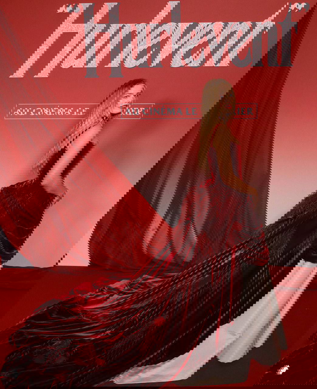 Марго Робби в профиль на фоне постера «Hurlevent» в Париже: боковой ракурс демонстрирует сложное драпирование и длинный шлейф платья.