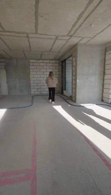 Настасья в пустой просторной комнате с незавершённой отделкой; на полу маркировочные линии и длинные тени от панорамных окон.