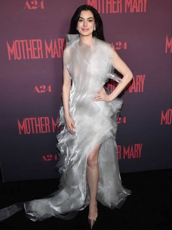 Ещё один кадр на красной дорожке: платье с волнообразными слоями, яркие вспышки фотокамер и фон с названием фильма.